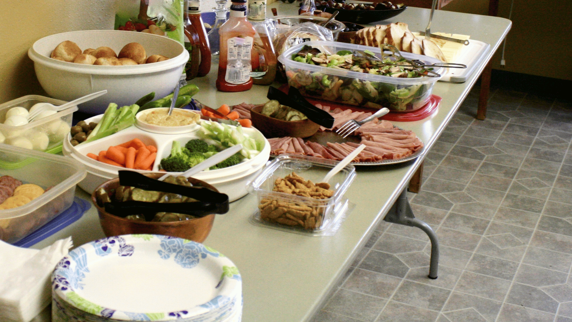 A colorful potluck table with labeled dishes and coordinated serving utensils planned in Recipe Memory