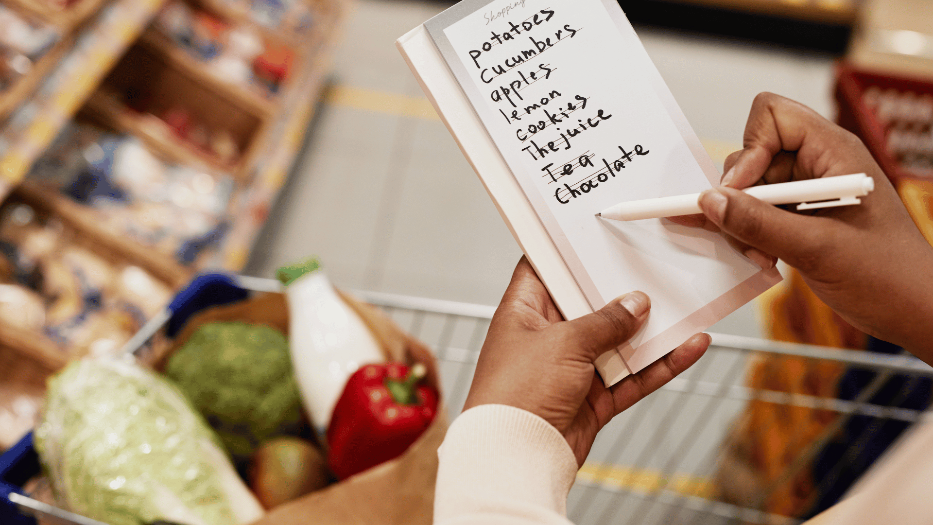 Organized grocery list on a phone next to a neatly packed cart, avoiding impulse buys